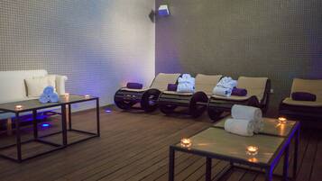 A spa area with massage chairs, a wooden floor, and tables with candles.