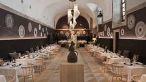 Un comedor amplio con mesas dispuestas para una comida, una pieza decorativa central y adornos de pared con diseños.