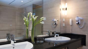 Un baño moderno con dos lavamanos, un espejo grande y un secador de pelo en la pared.