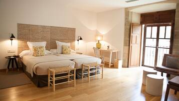 Une chambre à coucher avec un grand lit, deux tables de chevet, une chaise, un bureau et une fenêtre donnant sur un beau paysage.