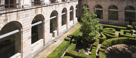Un patio con un edificio que tiene ventanas de arco y un campanario.