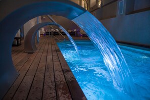 Un espace piscine doté d’une terrasse en bois et d’un élément décoratif aquatique.