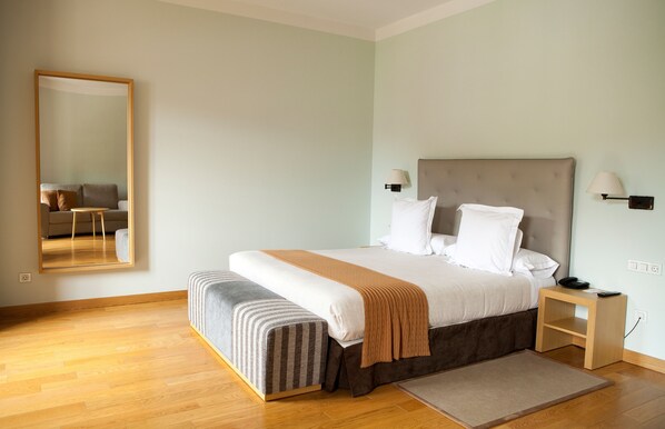 Ein ordentlich eingerichtetes Schlafzimmer mit Bett, Nachttischen, einem Spiegel und einem kleinen Tisch.
