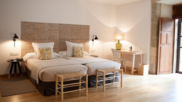 A bedroom with a large bed, two bedside tables, a desk, and a chair.