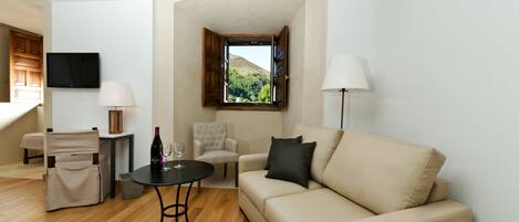A living room with a sofa, armchair, and a table with a bottle and glass.