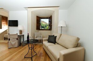 Relax in this stylish living room with a sofa, coffee table, and TV, offering a serene view of the surrounding hills.