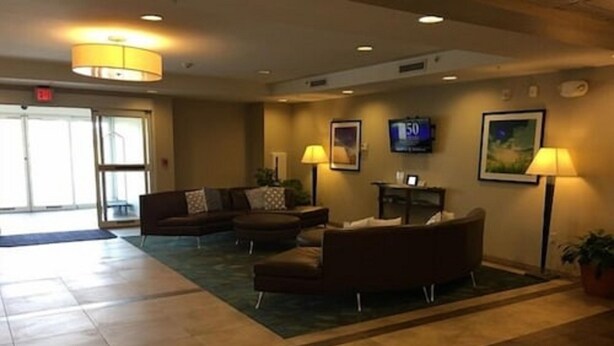 Un hall con sofá, sillones, televisión y mostrador de recepción.