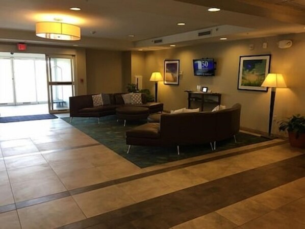 A lobby with a sofa, armchairs, a TV, and a reception desk. - Candlewood Suites Sidney by IHG (Sidney)