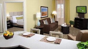 Habitación de hotel con comedor, sofá, televisión y cama.