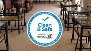 Un'area ristorazione con tavoli e sedie, un murale sulla parete e un logo che indica 'Clean & Safe' con 'Turismo de Portugal'.