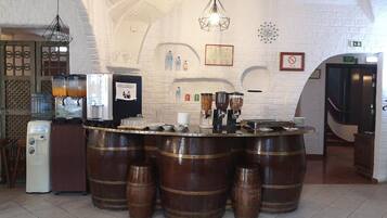 Zona de bar con pared de ladrillo blanco, barriles de madera y diverso equipamiento.