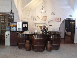 A bar area with a white brick wall, wooden barrels, and various bar equipment. - Hotel Nazareth (Lisbon)
