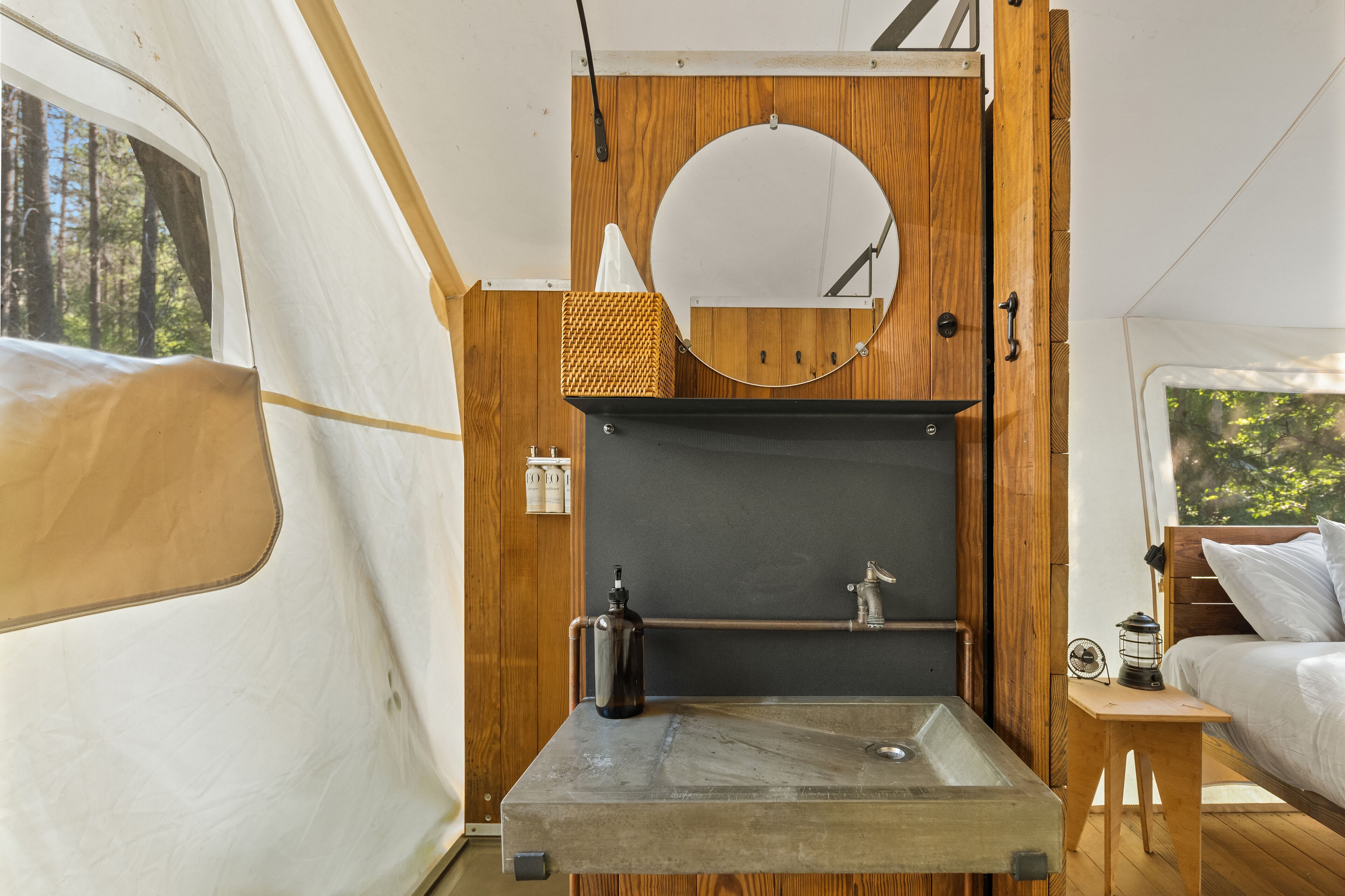 Un intérieur de camping-car compact et moderne, doté d’un évier intégré, d’éléments décoratifs en bois et d’une petite table de chevet.