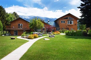 A two-story wooden cabin with a balcony, surrounded by a well-maintained lawn and garden. - Bad Rock Bed and Breakfast Inn (Columbia Falls)