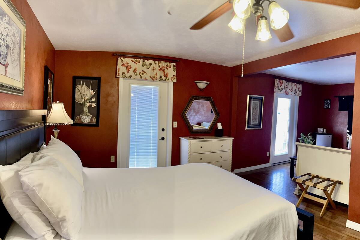 A bedroom with a bed, a dresser, a mirror, and a ceiling fan.