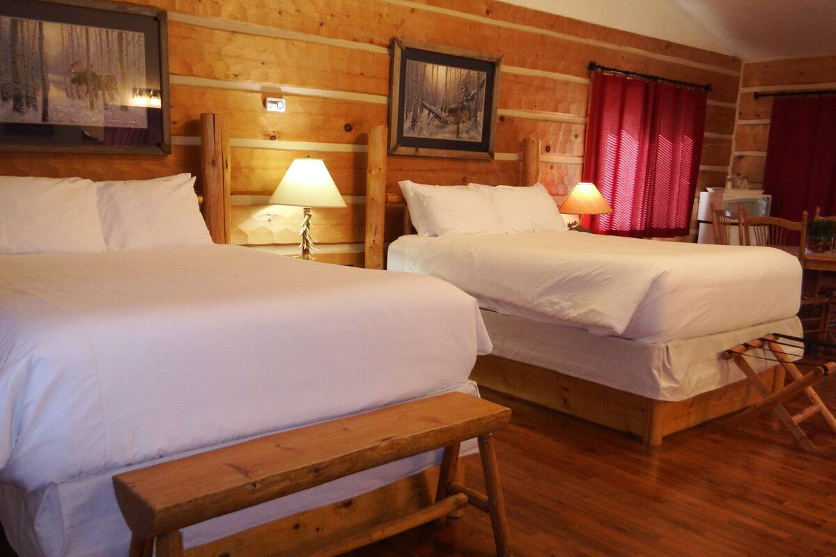 A cozy room with two wooden beds, a bench, and a wooden floor.