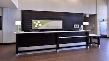 A reception desk with a flat-screen TV, a digital clock, and a sign for the Holiday Inn.