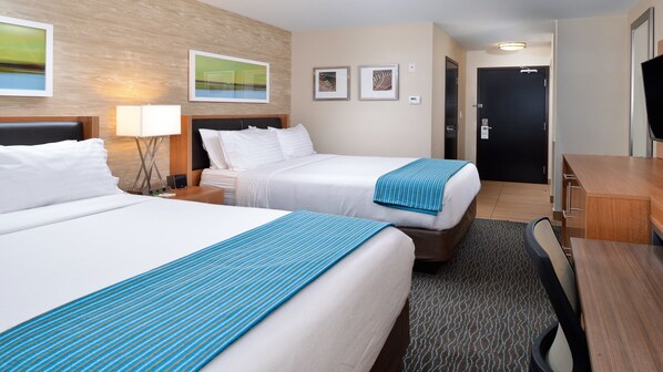 A hotel room with two beds, a desk, a chair, a TV, and artwork on the walls. - Holiday Inn Hotel & Suites Edmonton Airport & Conference Ctr by IHG (Nisku)