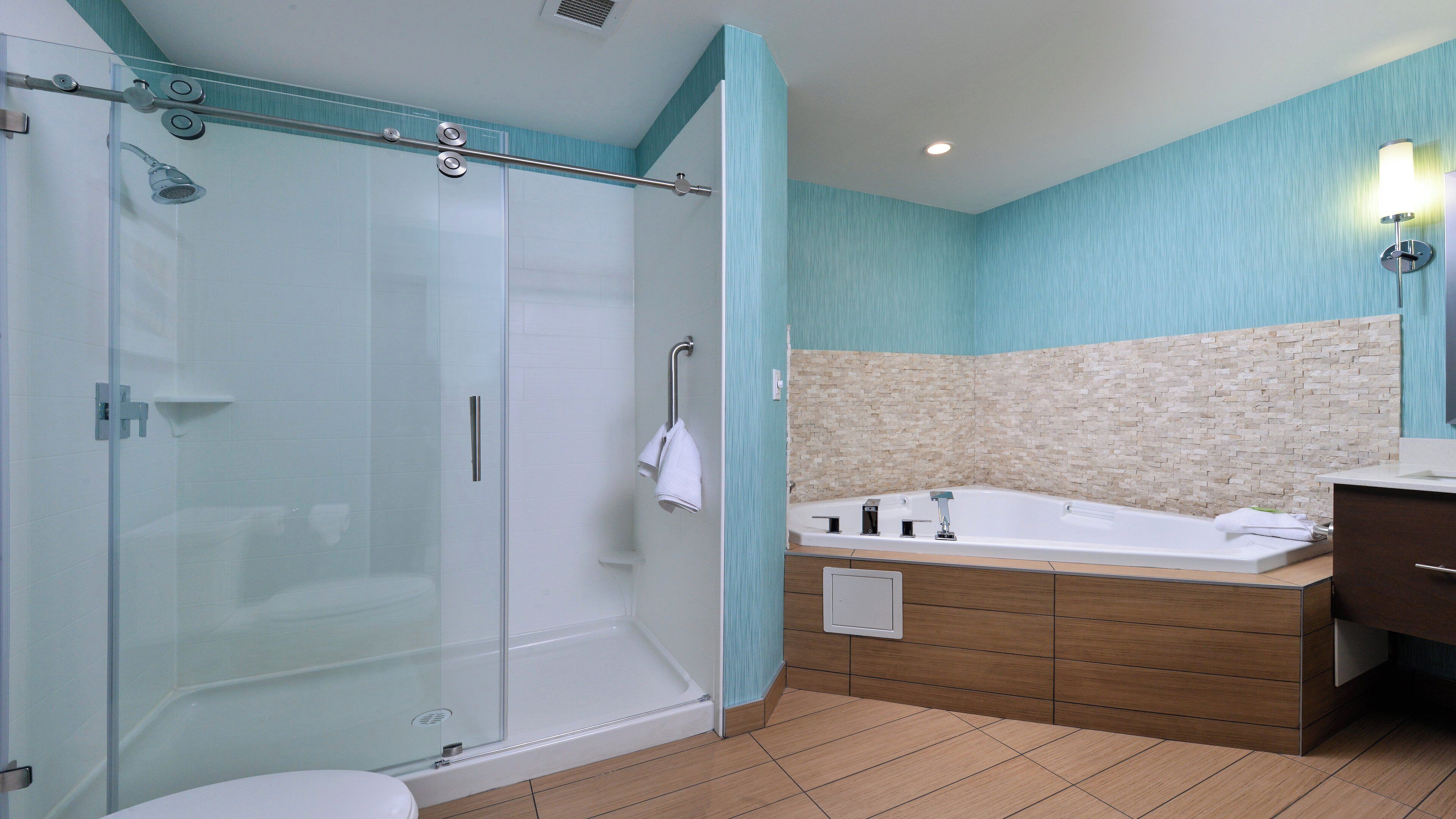 A modern bathroom with a glass shower enclosure, a freestanding bathtub, and a wooden vanity.