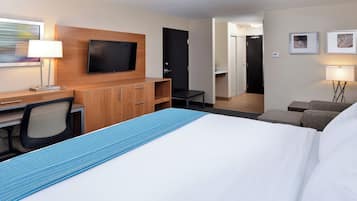 Una habitación de hotel con cama, escritorio, silla, televisor, armario y baño.