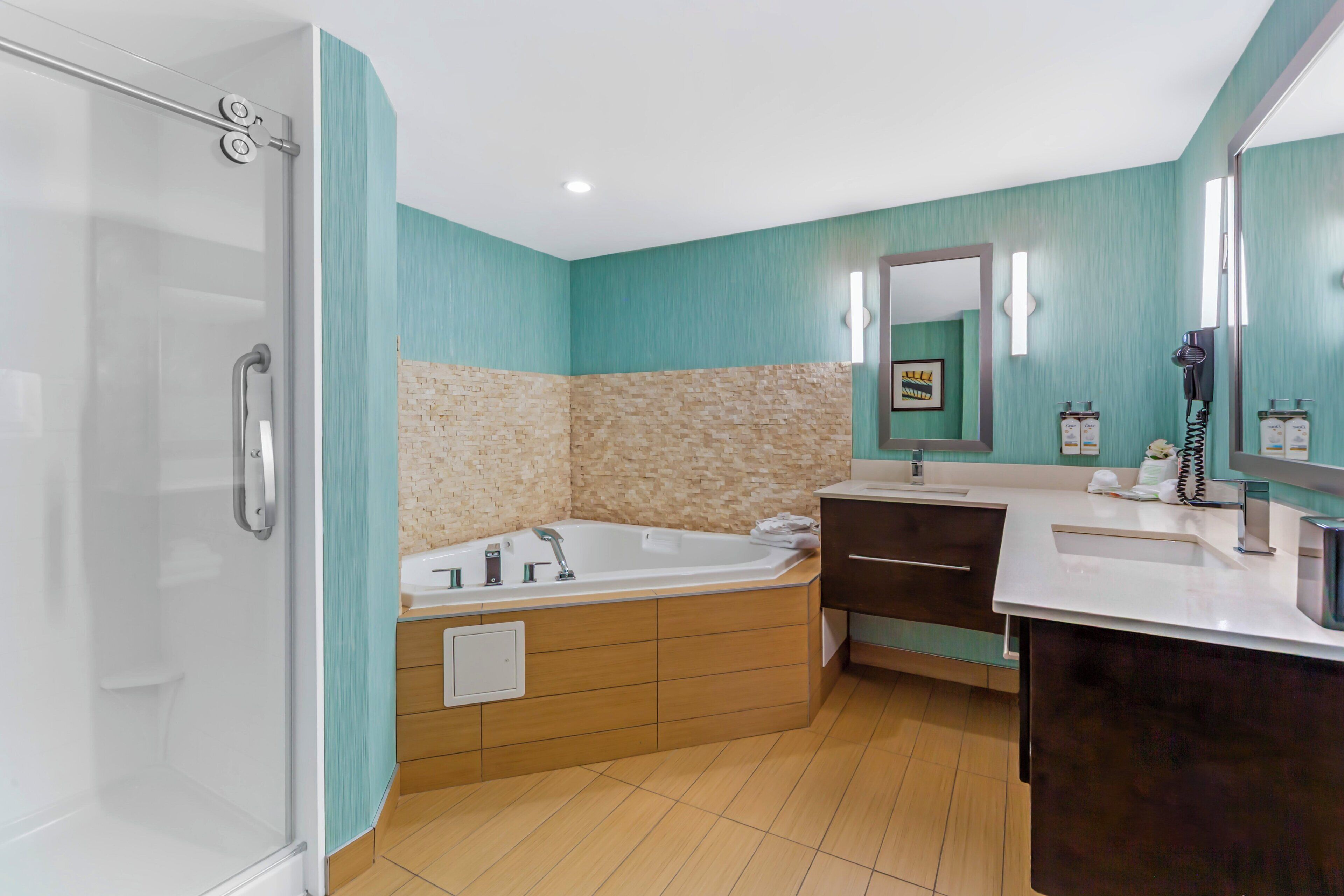 A bathroom with a glass shower enclosure, a freestanding bathtub, a vanity with a mirror, and a sink.