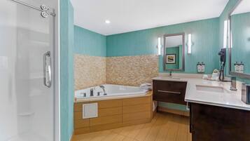 A bathroom with a glass shower enclosure, a freestanding bathtub, a vanity with a mirror, and a sink.