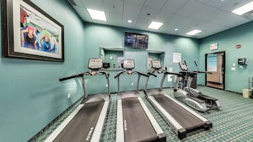 A fitness center with treadmills and exercise equipment, a clock, and a framed picture on the wall.