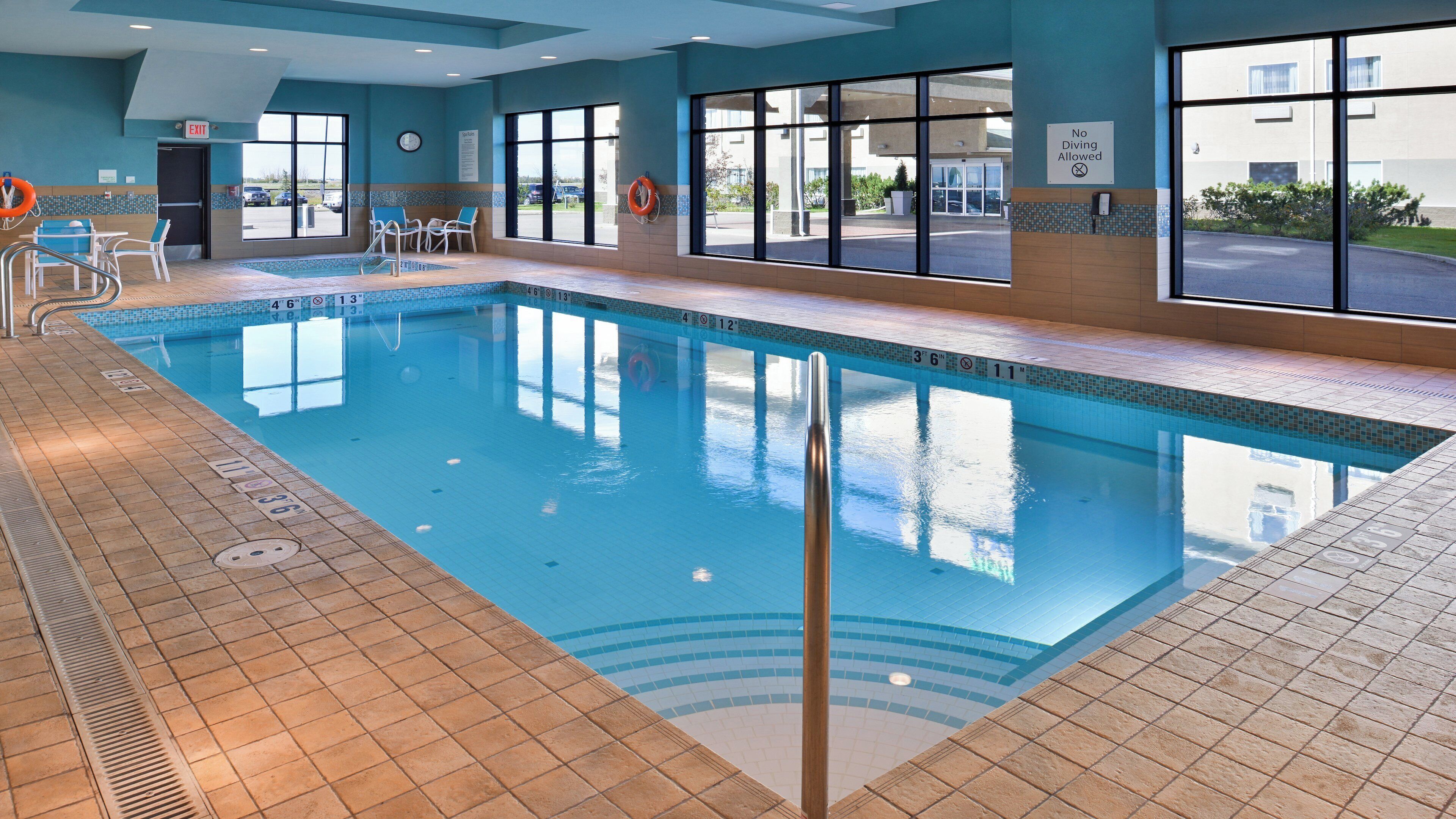 An indoor swimming pool with clear water, marked depth lines, and a lifebuoy.