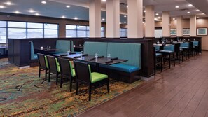 A hotel dining area with booths and tables, large windows, and a patterned carpet. - Holiday Inn Hotel & Suites Edmonton Airport & Conference Ctr by IHG (Nisku)