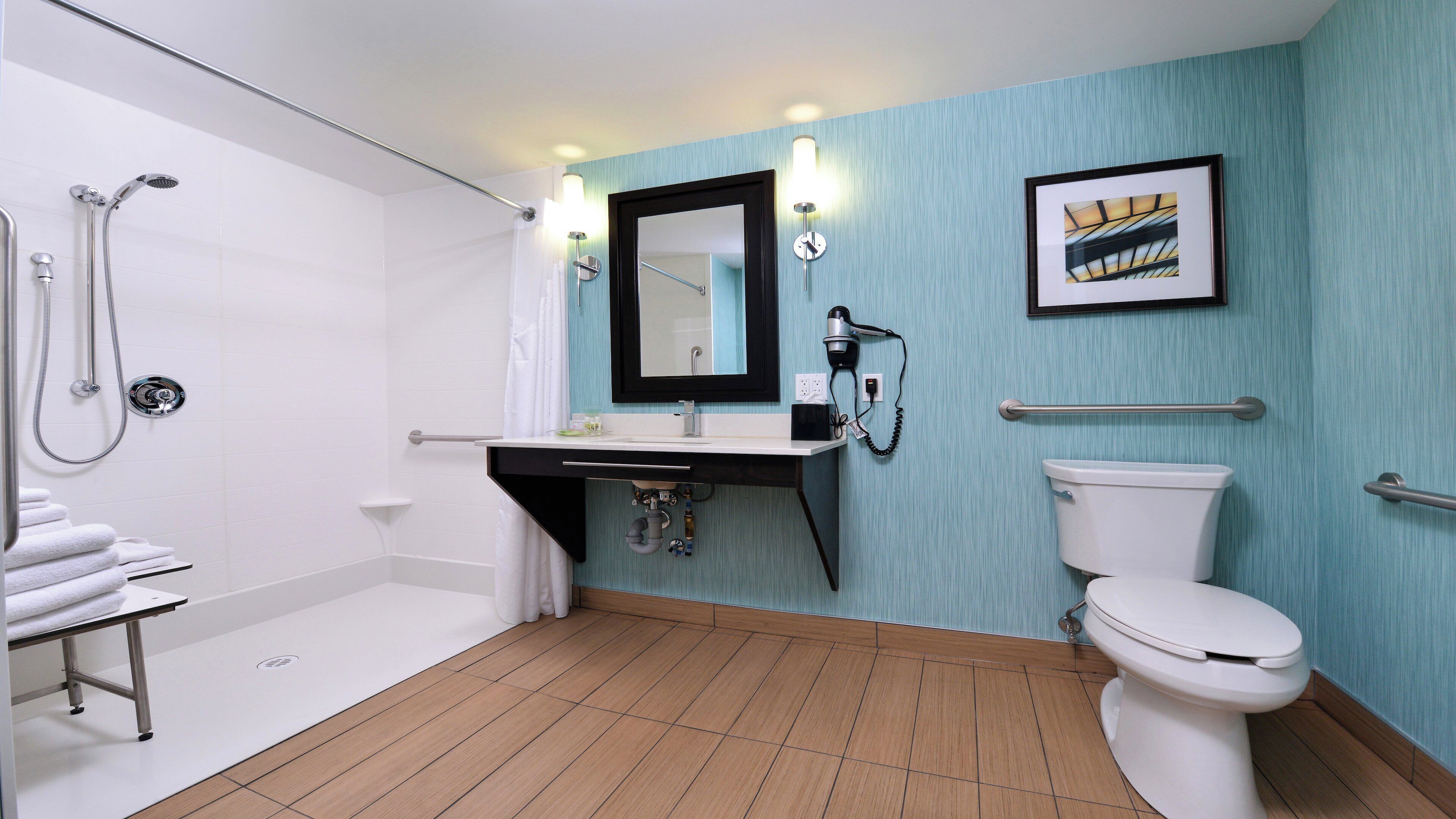 A bathroom with a shower, toilet, sink, and a towel rack.