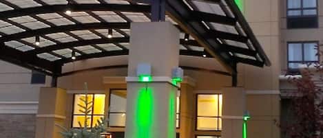 Un hôtel Holiday Inn doté d’une entrée couverte et d’un sapin de Noël en premier plan.