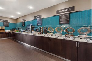 Zona de bufé con secciones identificadas para comidas calientes, productos horneados recién hechos y cereales.