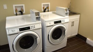 A laundry room with two front-loading Whirlpool washers, a sink, and a cabinet. - Holiday Inn Hotel & Suites Edmonton Airport & Conference Ctr by IHG (Nisku)