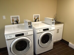 A laundry room with two front-loading Whirlpool washers, a sink, and a cabinet. - Holiday Inn Hotel & Suites Edmonton Airport & Conference Ctr by IHG (Nisku)