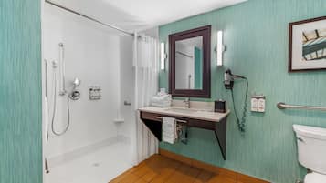 Un baño con ducha, lavamanos, espejo e inodoro.