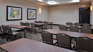 A conference room with tables and chairs, framed artwork on the walls, and an exit sign. - Holiday Inn Hotel & Suites Edmonton Airport & Conference Ctr by IHG (Nisku)
