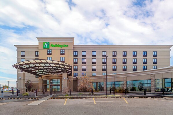 A Holiday Inn hotel with a covered entrance and a parking lot. - Holiday Inn Hotel & Suites Edmonton Airport & Conference Ctr by IHG (Nisku)