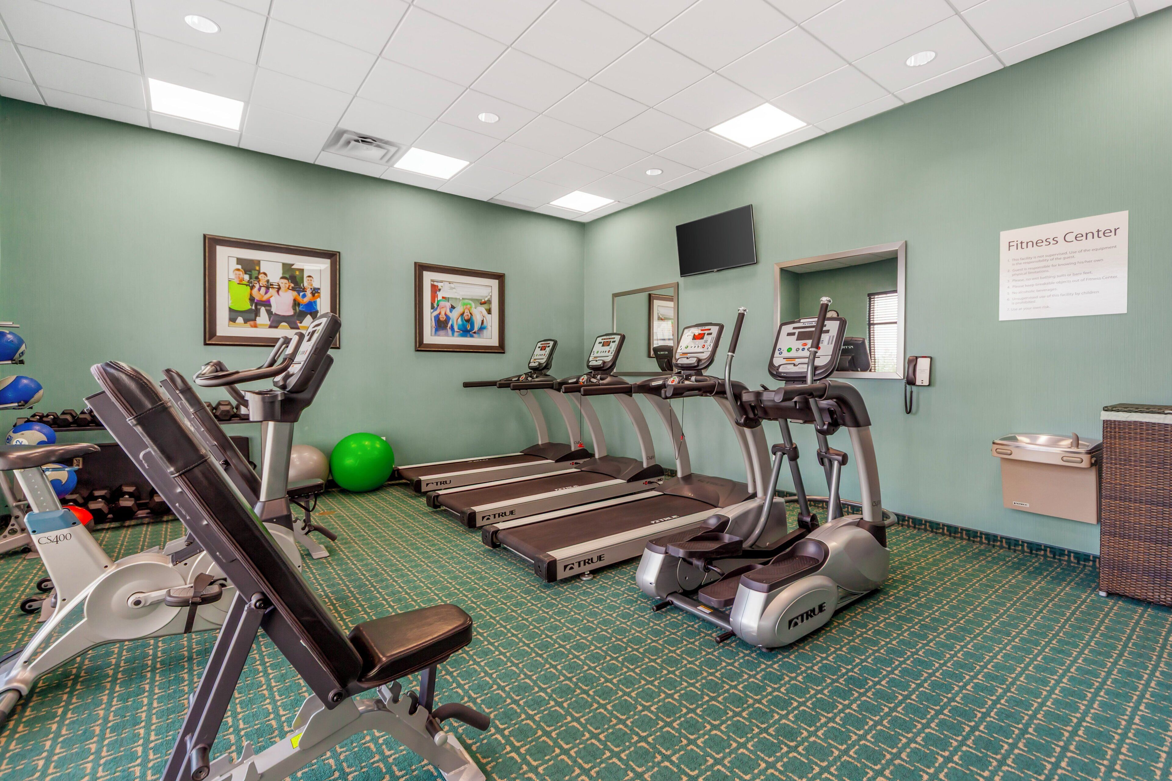 A fitness center with treadmills, stationary bikes, and exercise balls.