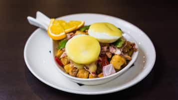 Um prato branco com um alimento que contém ovos, fatias de laranja e legumes picados.