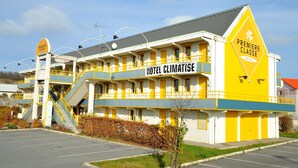 Un hotel llamado "Hotel Climatise" con una decoración en amarillo y blanco, que presenta un letrero llamativo y una escalera que conduce a la entrada.