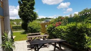 Un patio al aire libre con mesas de picnic y plantas en macetas.