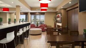 Un comedor moderno con barra, disposición de asientos y un gran ventanal que proporciona luz natural.