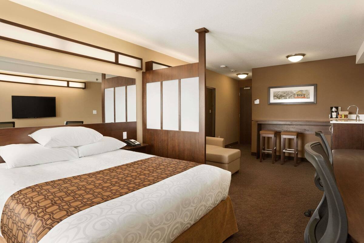 Una habitación de hotel con una cama grande, un escritorio y una zona de bar.