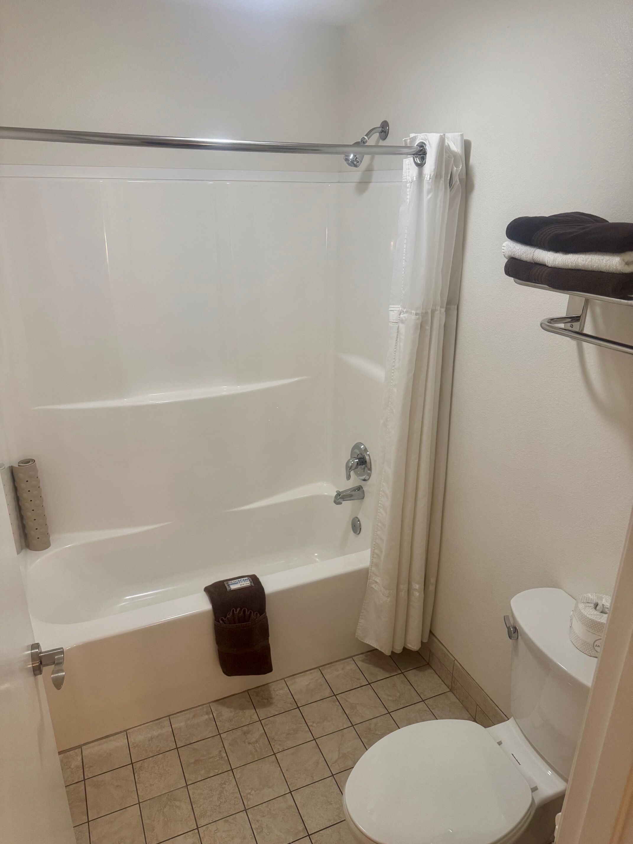 A bathroom with a bathtub, toilet, and a towel rack.