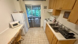 Una cocina compacta equipada con refrigerador, microondas, estufa, lavaplatos y gabinetes de madera.