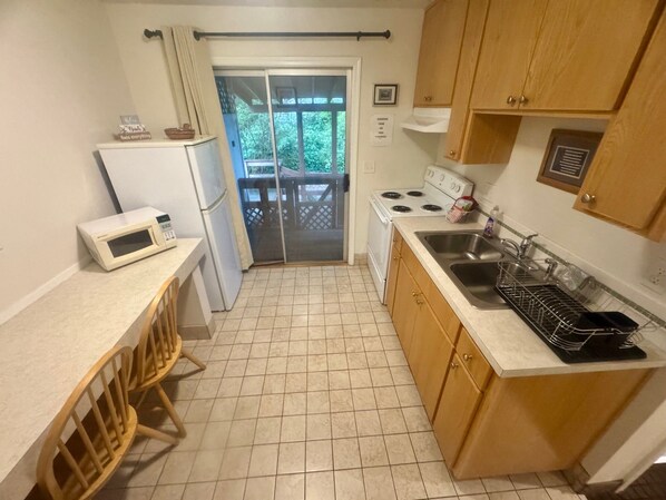 Una cocina compacta equipada con refrigerador, microondas, estufa, lavaplatos y gabinetes de madera.