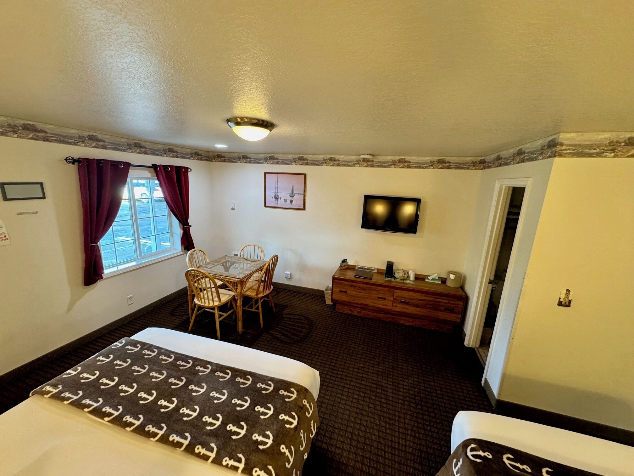 Une chambre d’hôtel équipée d’un lit, d’un bureau, d’une chaise, d’une télévision et d’une fenêtre avec des rideaux.