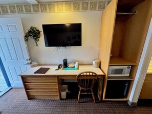 Un espacio de trabajo funcional con escritorio, silla y televisor de pantalla plana montado en la pared.