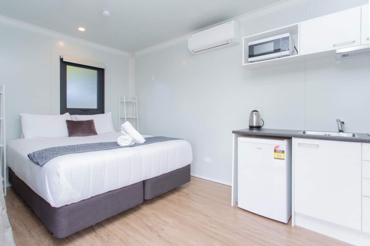 Een hotelkamer met een bed, een kitchenette en een magnetron.