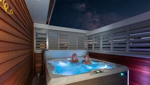 Un bain à remous pour deux personnes, une terrasse en bois et un ciel étoilé.